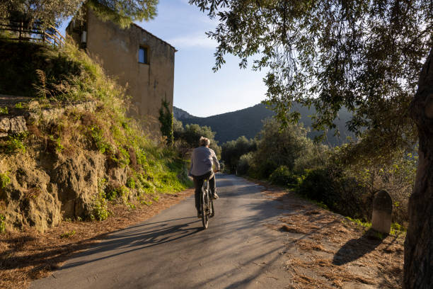 istock Mature man rides bicycle on country road 2184390674