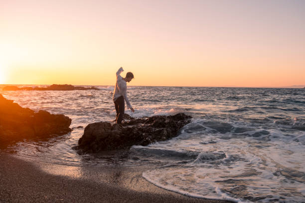 istock Young man having a vacation alone and having fun at the sea at sunset 2184392062