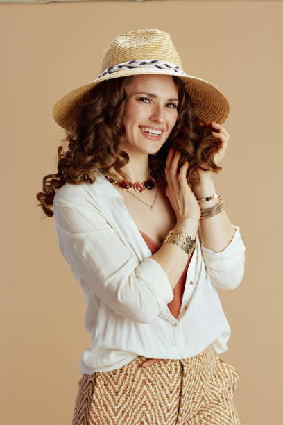 smiling woman in blouse and shorts on beige stock photo