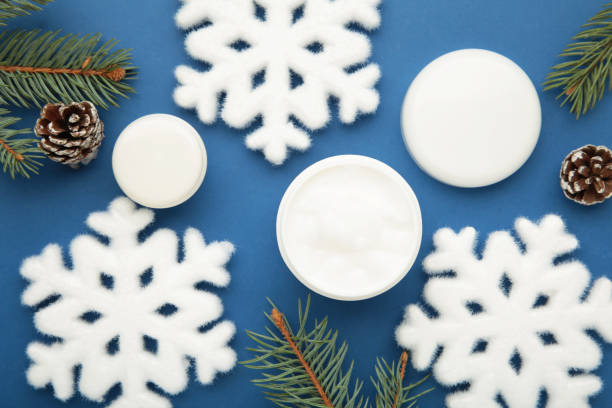 istock Cold protecting winter cream concept. Jar cosmetics with snowflakes and fir tree branches on blue background. Winter seasonal skin care 2184397375