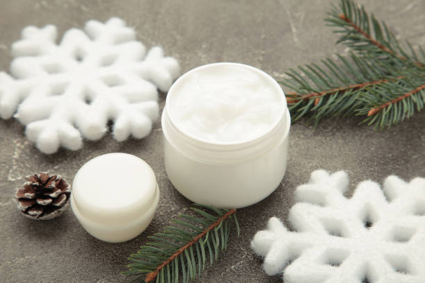 istock Cold protecting winter cream concept. Jar cosmetics with snowflakes and fir tree branches on grey background. Winter seasonal skin care 2184397390