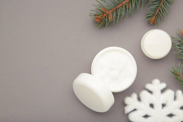 istock Cold protecting winter cream concept. Jar cosmetics with snowflakes and fir tree branches on grey background. Winter seasonal skin care 2184397400