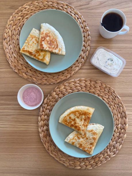 Quesadillas served on round plates placed on woven placemats, showcasing a culinary delight. Texture and golden tone of the tortillas, inviting a comforting dining experience. Mexican cuisine