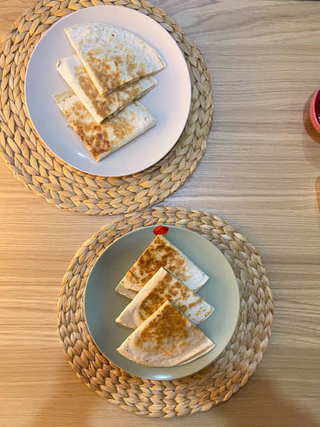 Quesadillas served on round plates placed on woven placemats, showcasing a culinary delight. Texture and golden tone of the tortillas, inviting a comforting dining experience. Mexican cuisine