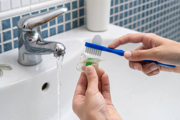 istock Hands brushing dental retainer under running tap water 2184414309