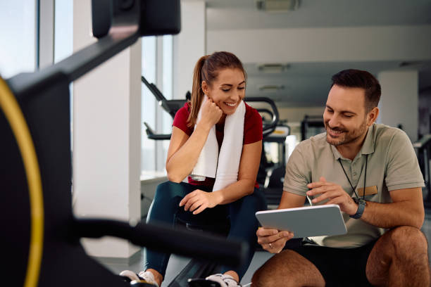 istock Happy athletic woman and her personal trainer going through exercise plans on touchpad in a gym. 2184415071
