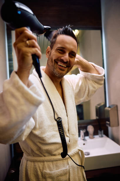 istock Happy man using hair dryer in the bathroom. 2184415480