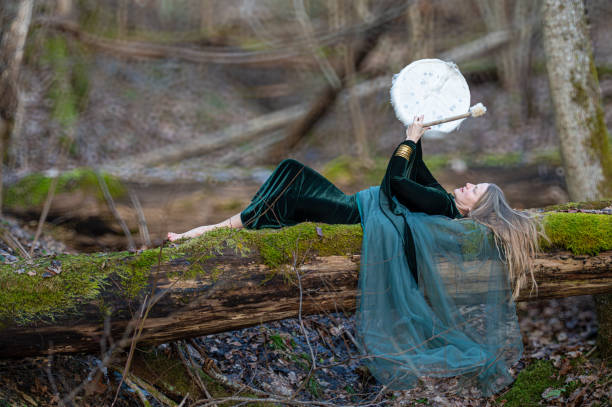 Woman playing a drum in a forest. Shallow depth of feld