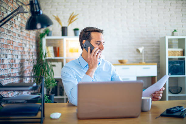 istock Young man talking on the phone in his home office 2184421193