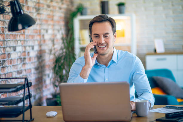 istock Young man talking on the phone in his home office 2184421264