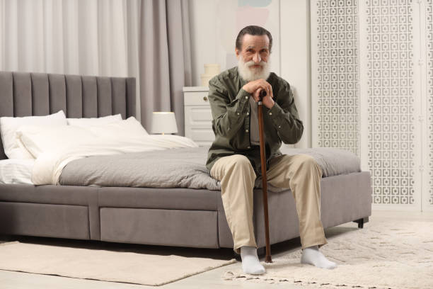 istock Senior man with walking cane on bed at home 2184421428