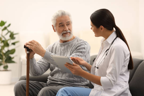 istock Smiling nurse with tablet and elderly patient on sofa in hospital 2184422059