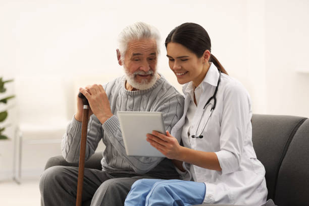 istock Smiling nurse with tablet and elderly patient on sofa in hospital 2184422083