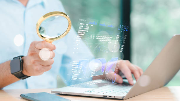 istock A professional using a magnifying glass to examine digital data on a laptop, symbolizing meticulous analysis and data-driven decision-making in a modern workspace 2184422938