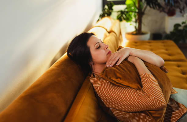 istock Woman Relaxing on a Comfortable Sofa in Sunlit Living Room 2184423364