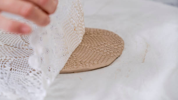 istock In an art studio with an environment adorned with artistic paintings in the background, a beautiful middle-aged woman artist is working on a lace pattern design on a clay plate at a table 2184423777