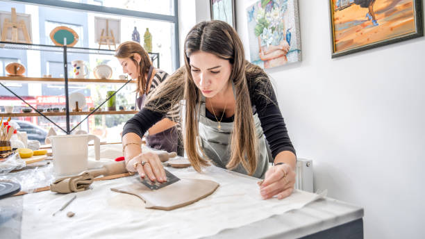 istock In an art studio with an environment adorned with artistic paintings in the background, two beautiful middle-aged artist friends are working on clay shaping at a table 2184423805
