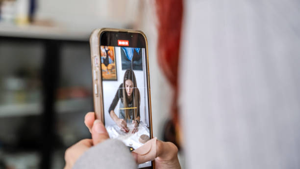 istock In an art studio with an environment adorned with artistic paintings in the background, a beautiful middle-aged woman artist is shaping clay at a table, while a young woman next to her is taking a photo with her phone 2184423847