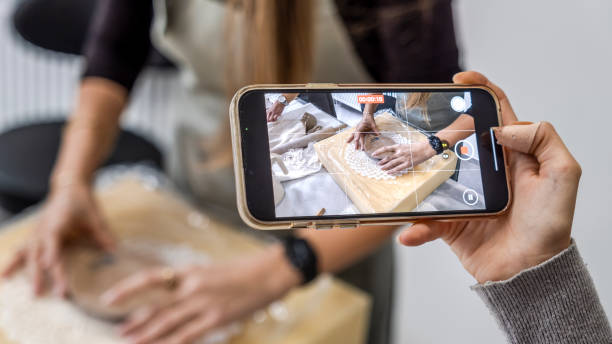 istock In an art studio with an environment adorned with artistic paintings in the background, a beautiful middle-aged woman artist is shaping clay at a table, while a young woman next to her is taking a photo with her phone 2184423865