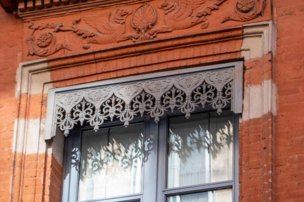 Ornate red building facade with a traditional balcony, featuring detailed railings, columns, and brickwork, showcasing rich historical architecture
