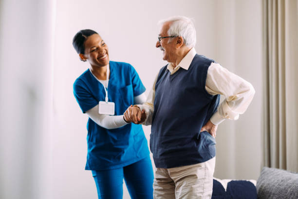 istock Smiling Nurse Assisting Happy Elderly Man in Relaxed Home Setting 2184430208