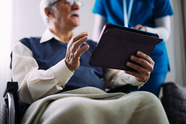 istock Elderly Man Using Tablet with Healthcare Professional Support 2184430261