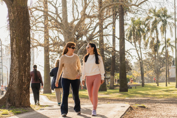 istock Two women walking and talking in a park on a sunny day 2184430786