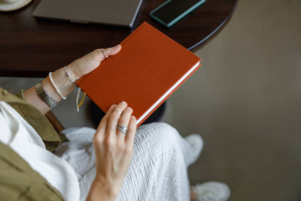 istock Hands Carefully Holding a Beautiful Notebook on a Warm Wooden Table in a Cozy Setting 2184433602