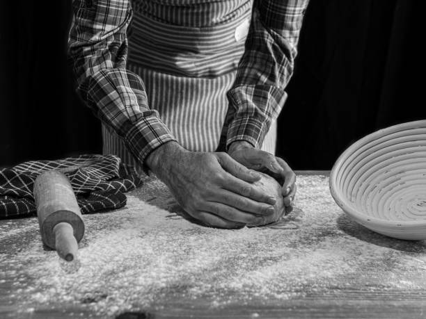 Baker making artisan bread. Bakery utensils. Black background. black and white photo