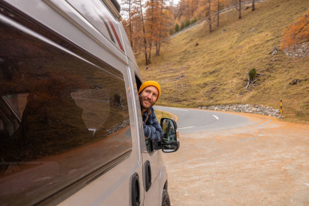 istock Man Looking Out from Camper Van on Scenic Road 2184442749