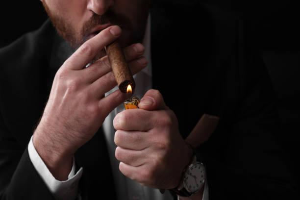 istock Man lightning cigar on black background, closeup 2184450993
