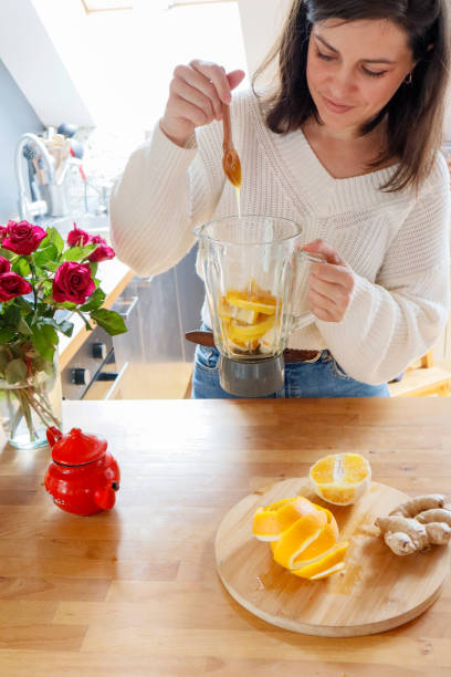 istock Woman adding honey to blender with orange and ginger for tea 2184461799