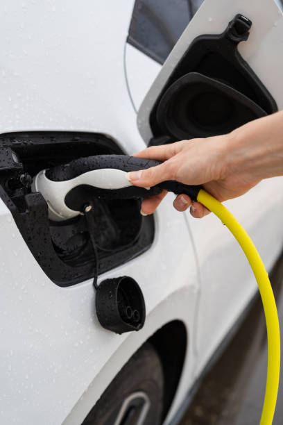 istock Woman's hand charging white electric car via plug 2184462533
