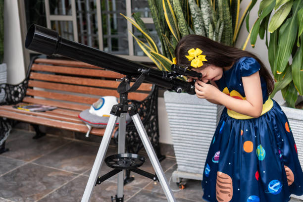 istock Girl looking through a telescope in a backyard 2184462986
