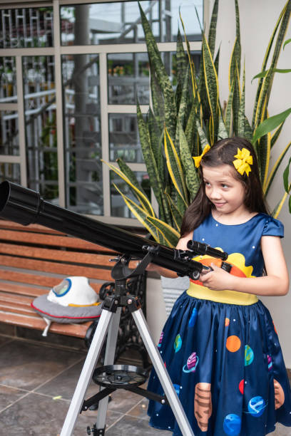 istock Girl standing by a telescope in a backyard setting 2184462987