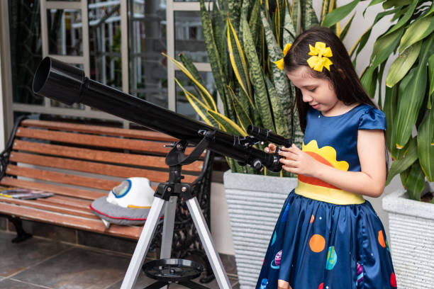 istock Young girl adjusting a telescope in a backyard setting 2184463004