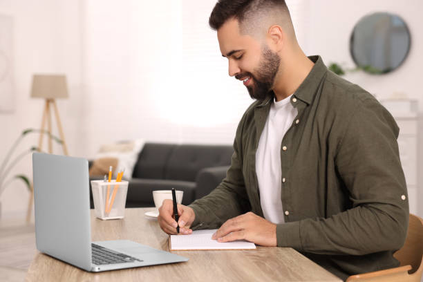 istock Young man writing in notebook at wooden table indoors 2184464405