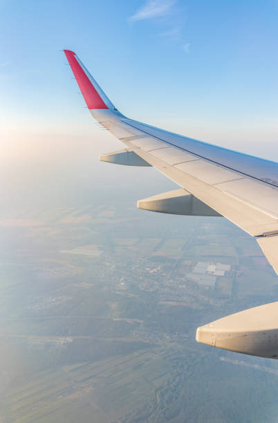 View from the airplane window at a beautiful cloudy sky and the airplane wing. Earth and sky as seen through window of an airplane.