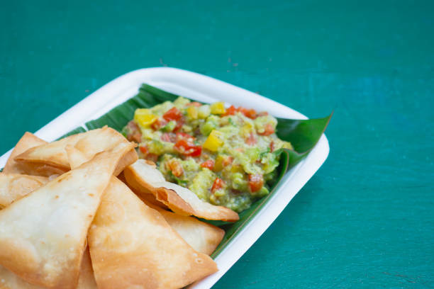 Tasty guacamole paired with crunchy tortilla chips on a biodegradable tray, ideal for topics on appetizers, eco-friendly dining, and delicious Mexican food.