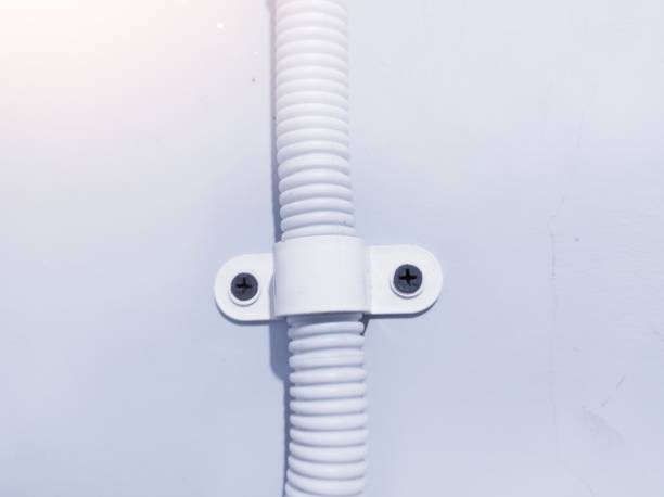 Installation flexible pipe for electric cable with clamp on the wall.