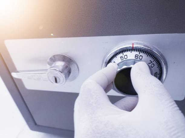 istock A person's hand wearing a glove is opening the security number on a money safe box. 2184477920