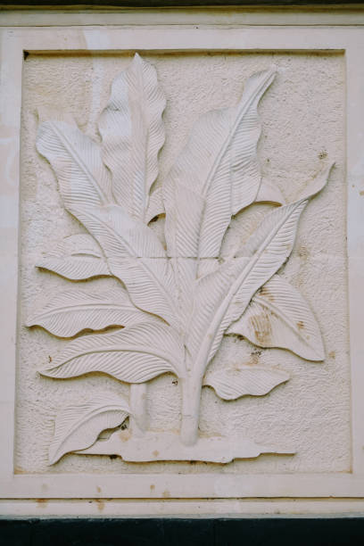 Bogor, November 9, 2024. A detailed carved stone relief depicting large, overlapping tropical leaves with textured lines, set within a rectangular frame.