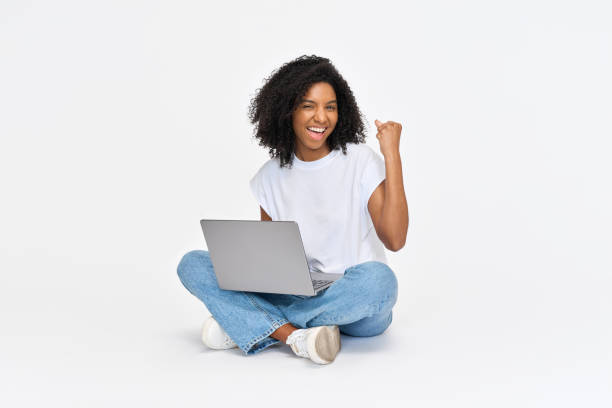 istock Happy African girl student winner sitting isolated on white using laptop. 2184496982