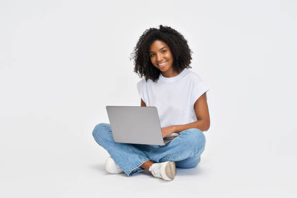 istock Happy young African woman student sitting isolated at white using laptop. 2184496997