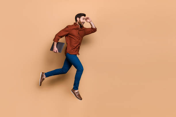 istock Full body portrait of energetic handsome guy jump run hand touch forehead look empty space isolated on beige color background 2184497251