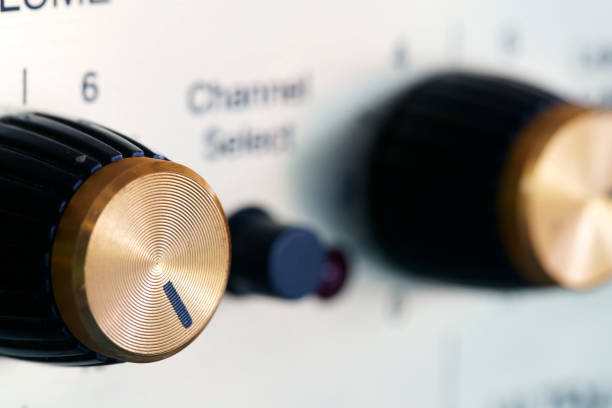 Close-up of a vintage audio receiver with knobs for volume and balance, featuring a green backlit display showing frequency and signal strength.