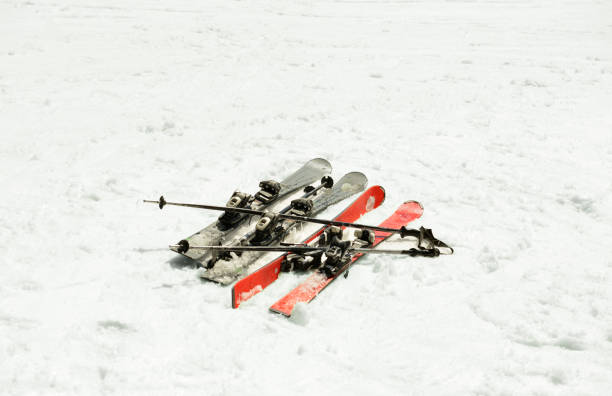 Skis and ski sticks on snow on background.