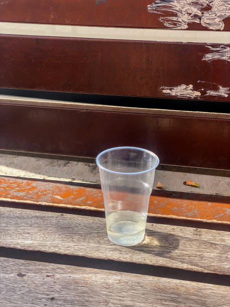 High angle view of a plastic drinking glass with liquid in it left on park bench