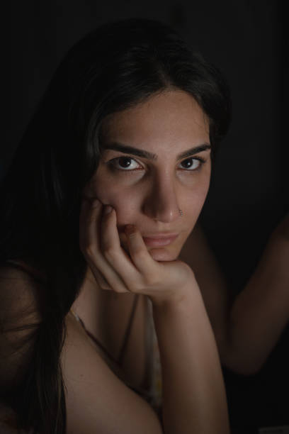 A close-up portrait of a woman in soft, dim lighting, expressing thoughtfulness and emotion. Perfect for creative and introspective projects.