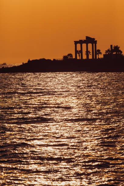 Side Apollo's temple silhouette at sunset, orange sky reflects on water. Vertical. Side ancient city, Antalya, Turkiye (Turkey)